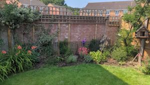 A brick wall surrounding a flower bed with a wood trellis added at the top to aid privacy.