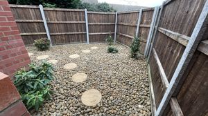 A wooden fenced and stone lined courtyard garden.
